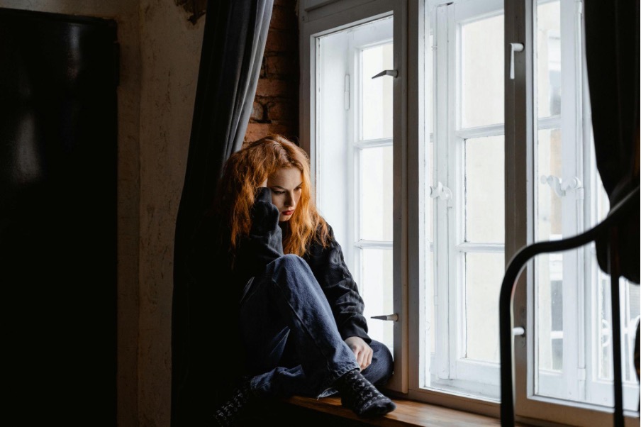 Woman sitting on windowsill practicing mindfulness