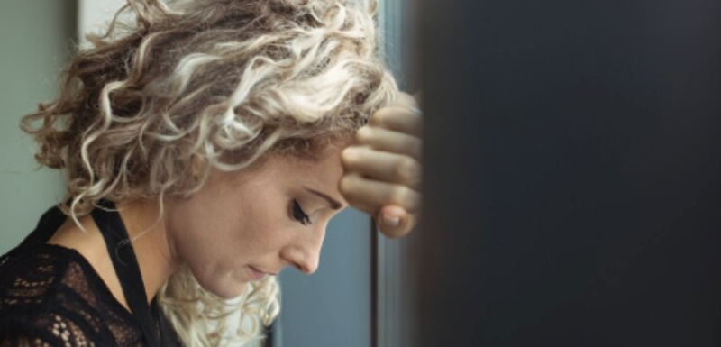 Woman leaning on something and looking down.